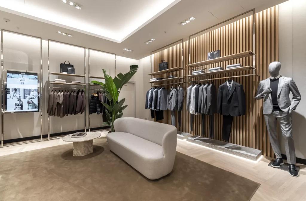 Espace conseil BOSS Parly 2 avec fauteuil, portants costumes, mobilier bois et éclairage intégré