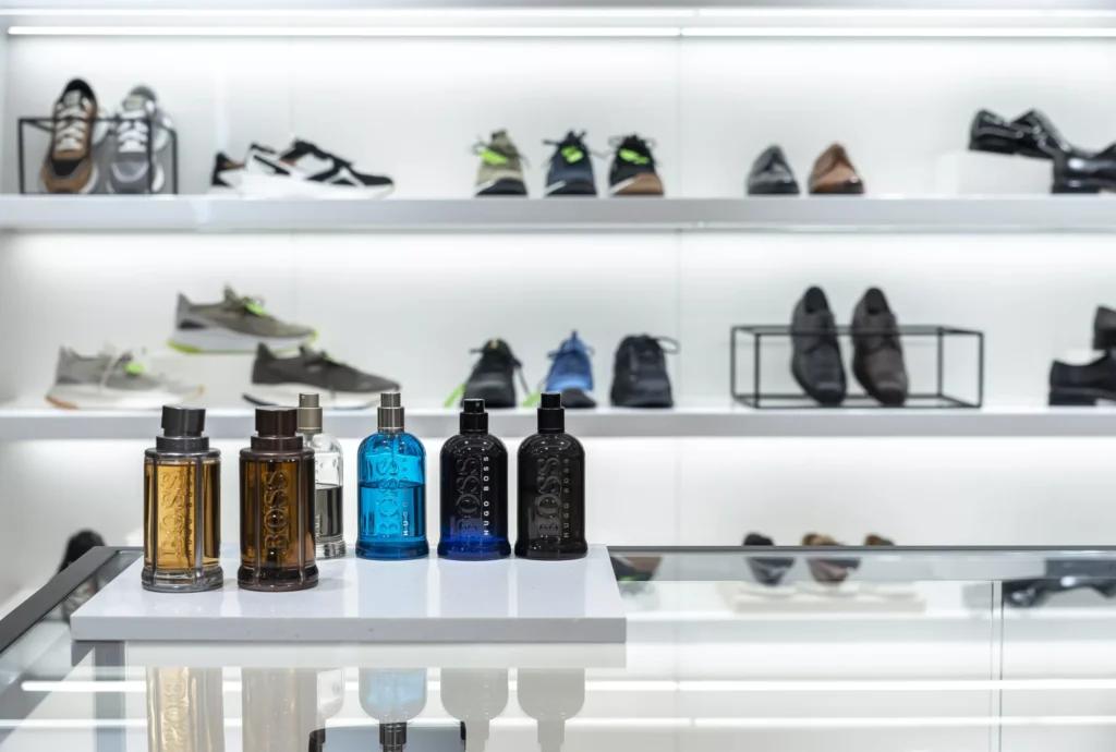Flacons de parfum BOSS présentés sur un comptoir avec linéaires chaussures en arrière-plan