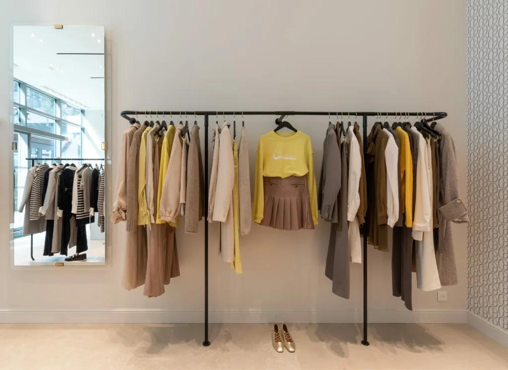 Portants vêtements dans la boutique Claudie Pierlot Grenoble avec mobilier minimaliste et touches de bleu