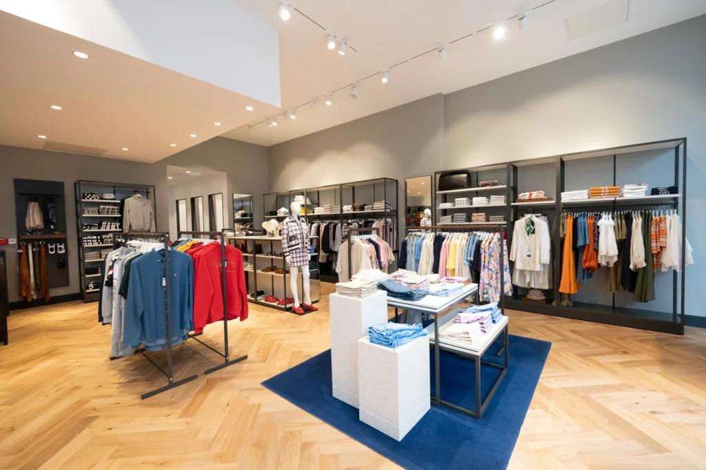 Collections prêt-à-porter GANT présentées sur portants et tables dans une boutique aménagée par L2A