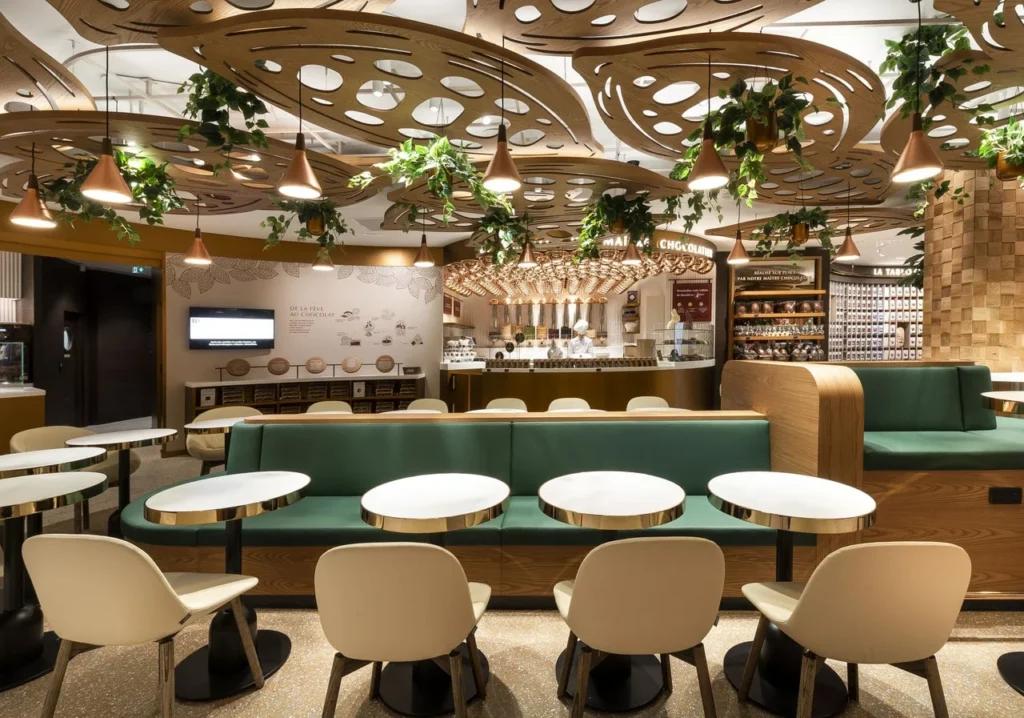 Espace dégustation du flagship Lindt Paris Opéra avec tables, assises et décor végétalisé