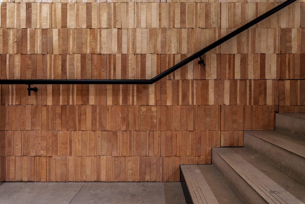 Escalier de la boutique MANGO Bordeaux avec mur en matériaux naturels et main courante noire