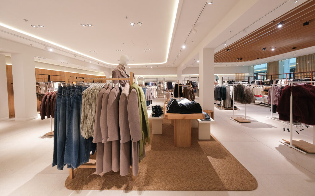 Espace central de la boutique MANGO Rosny avec portants, tables bois, mannequins et collections mode