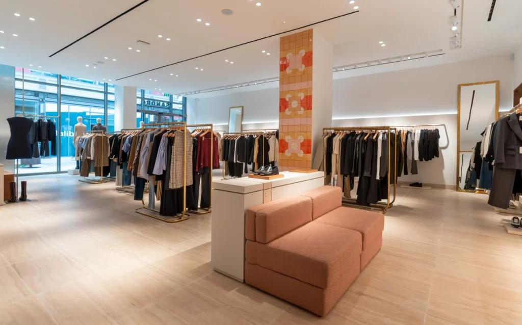 Vue grand angle de la boutique Sandro Grenoble avec portants, miroirs, éclairage et détails dorés
