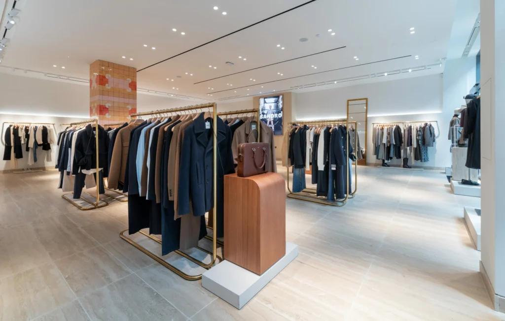 Portants vêtements dans la boutique Sandro Grenoble avec mobilier noir, éclairage et ambiance mode