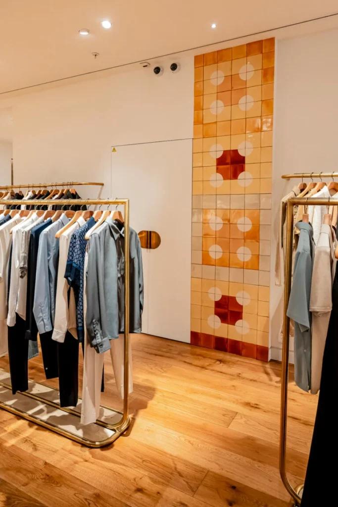 Portants vêtements dans la boutique Sandro La Défense avec éclairage retail et mobilier de présentation