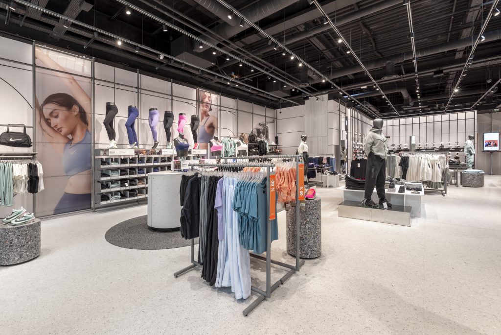Vue en angle du magasin Nike Aéroville avec mobilier retail, rayons sport et circulation client