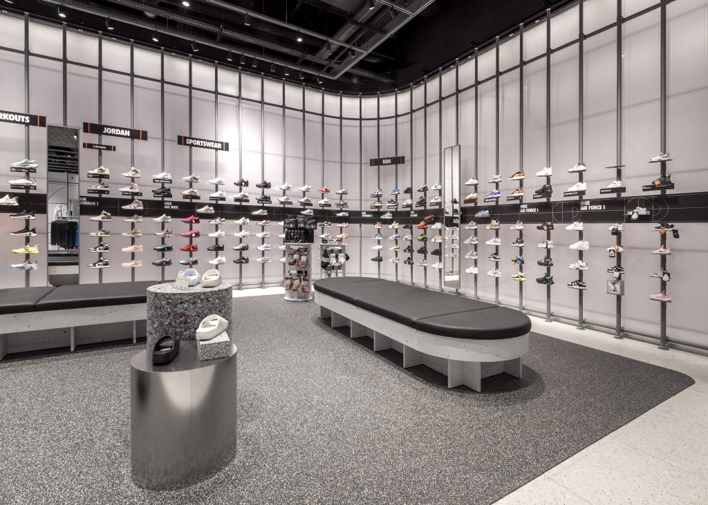 Linéaires de chaussures Nike dans le magasin Aéroville avec mobilier mural et éclairage intégré