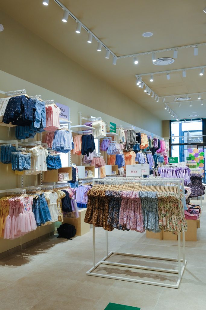 Rayons vêtements enfant dans la boutique Name It Giverny avec mobilier retail et présentation textile