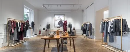 Intérieur de la boutique Sandro avenue Victor Hugo à Paris avec parquet en pointe de Hongrie, mobilier retail et portants dorés