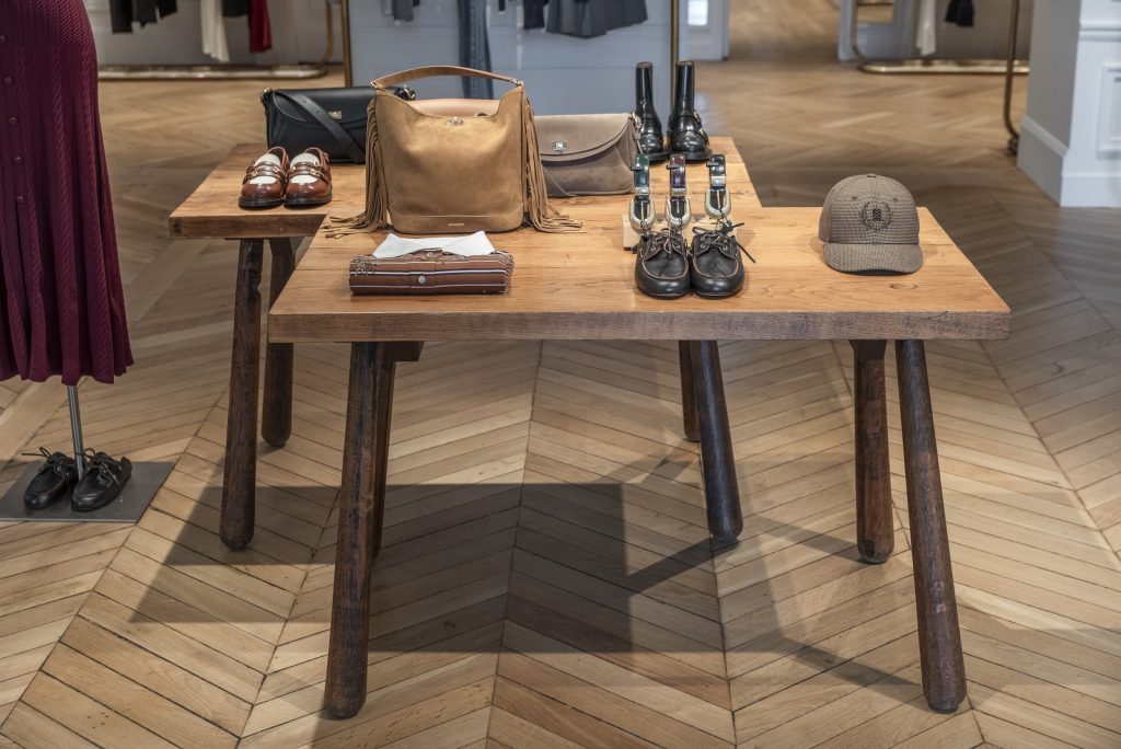 Table centrale de présentation dans la boutique Sandro Paris Victor Hugo avec sacs, chaussures et accessoires