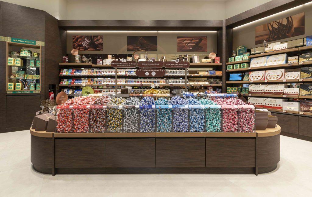 Linéaires de chocolats Lindt dans la boutique Cap 3000 avec mobilier bois et éclairage intégré