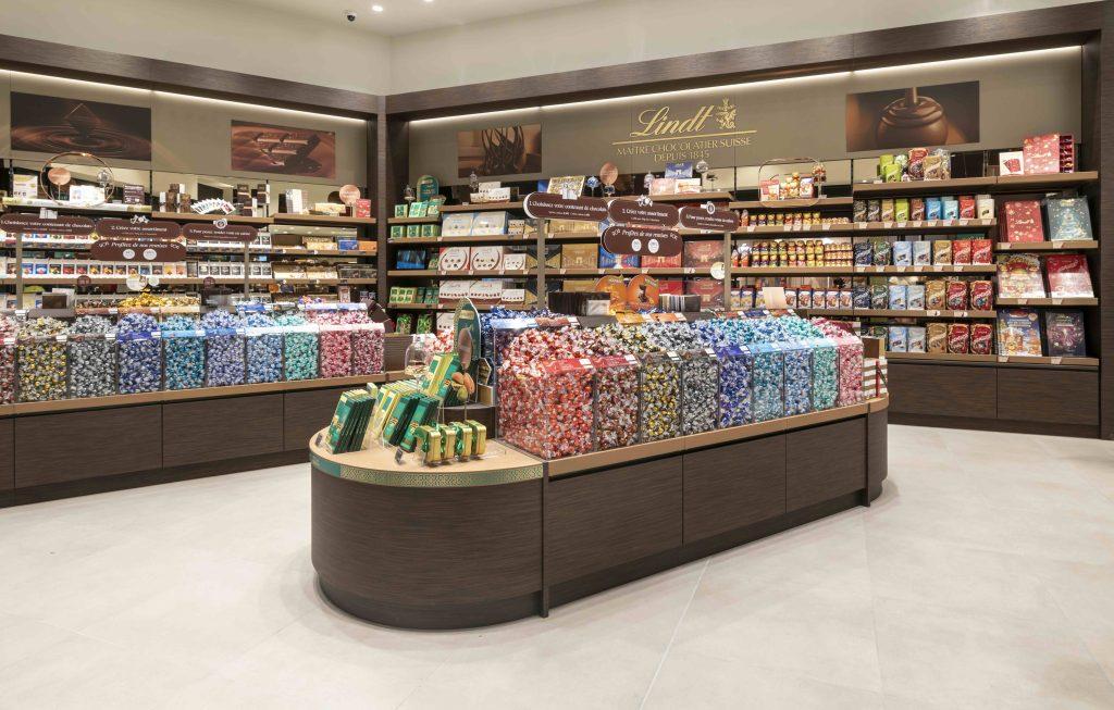 Vue en angle de la boutique Lindt Cap 3000 avec îlots de chocolats, linéaires muraux et mobilier retail