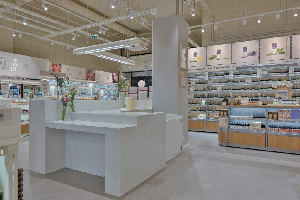 Comptoir central blanc dans la boutique Aroma-Zone Anglet avec fleurs, rayons soins et huiles essentielles