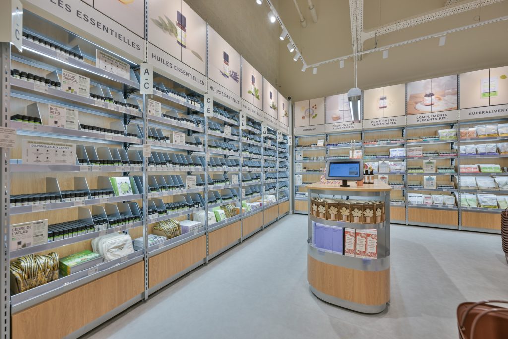 Linéaires d’huiles essentielles Aroma-Zone dans la boutique d’Anglet avec mobilier bois et éclairage intégré