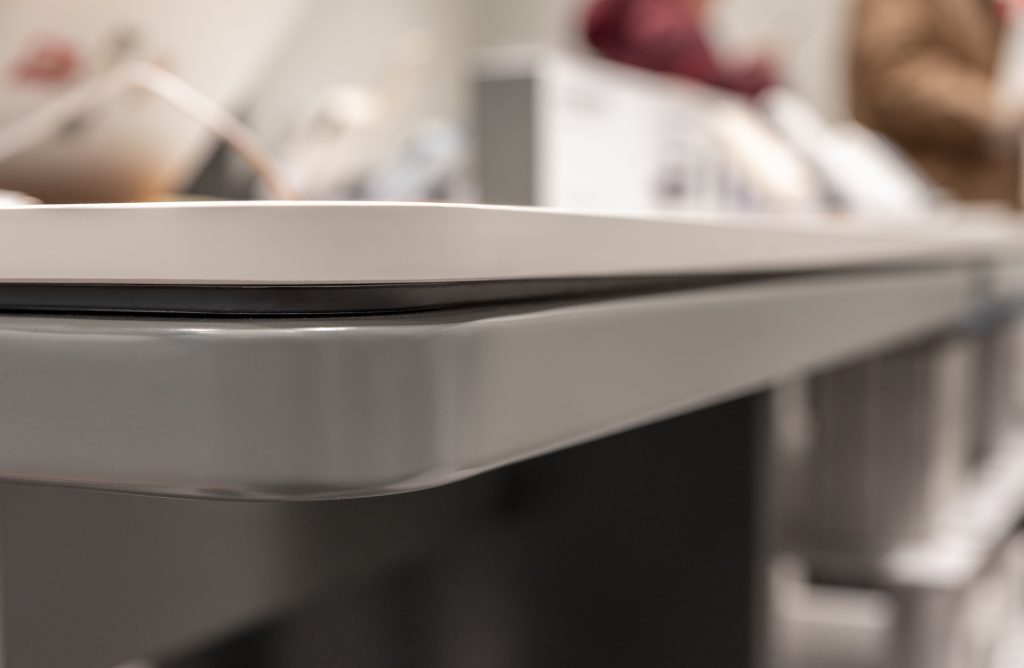 Détail du mobilier sur mesure du Xiaomi Store Créteil avec plateau blanc, piètement gris et finition arrondie