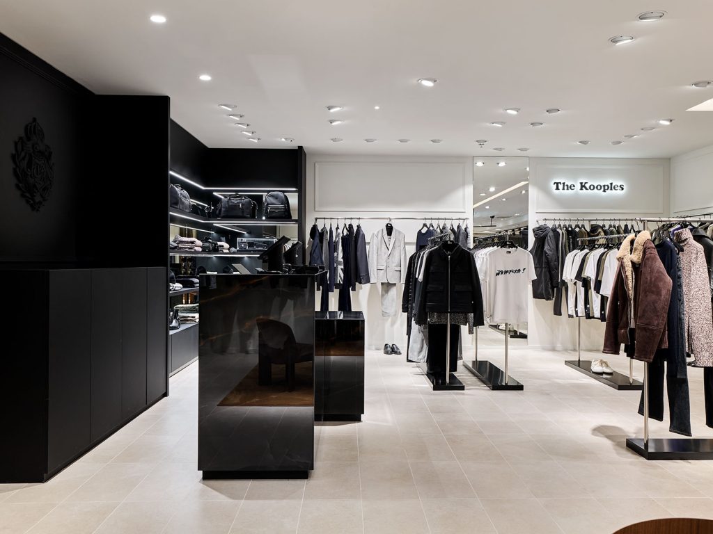 Vue globale du corner Homme The Kooples avec comptoir noir, mobilier sur mesure, portants et éclairage retail