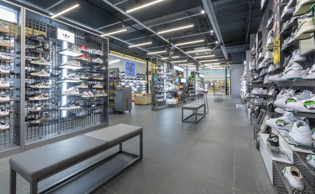 Vue intérieure de la boutique JD Sports Grenoble avec linéaires sneakers, mobilier mural et éclairage retail