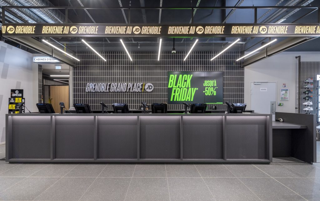 Espace caisse de la boutique JD Sports Grenoble avec comptoir, signalétique lumineuse et habillage mural