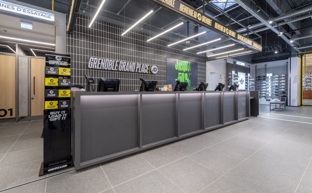 Comptoir caisse JD Sports Grenoble Grand Place avec cabines d’essayage, signalétique et mobilier gris
