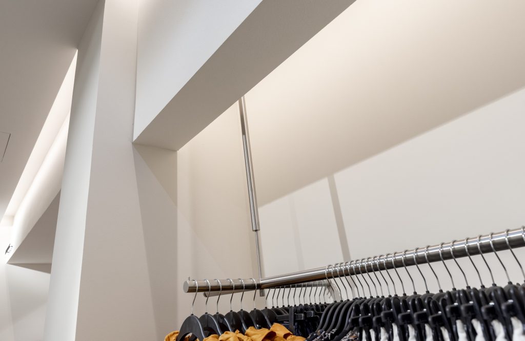 Présentoir central du magasin H&M Rosny avec sacs, accessoires, étagères claires et verre