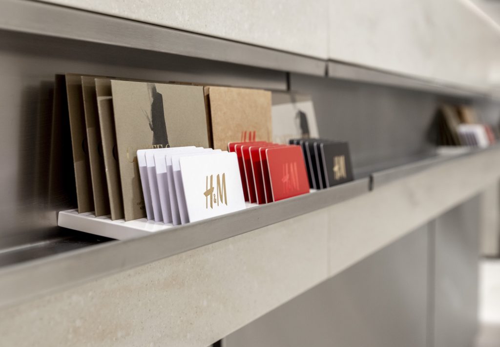 Détail du mobilier H&M Rosny avec cartes cadeaux, tablette intégrée et finition minérale