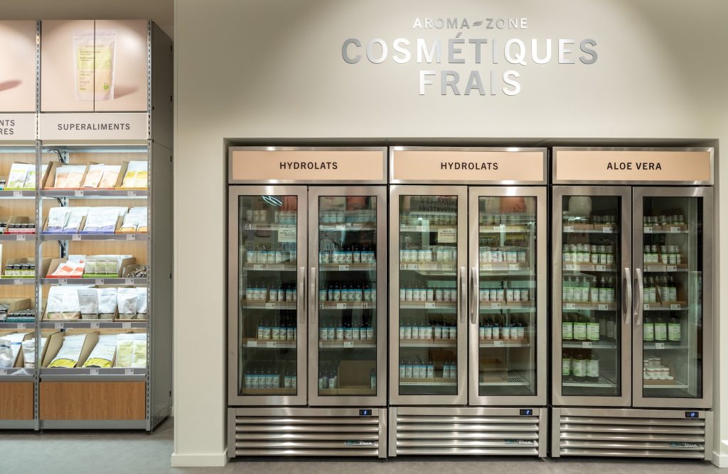 Détail des rayons produits dans la boutique Aroma-Zone Vélizy avec mobilier retail et éclairage intégré