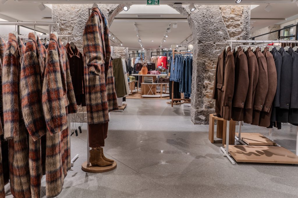 Parcours client dans la boutique MANGO Lyon avec arches en pierre, portants vêtements et mobilier retail