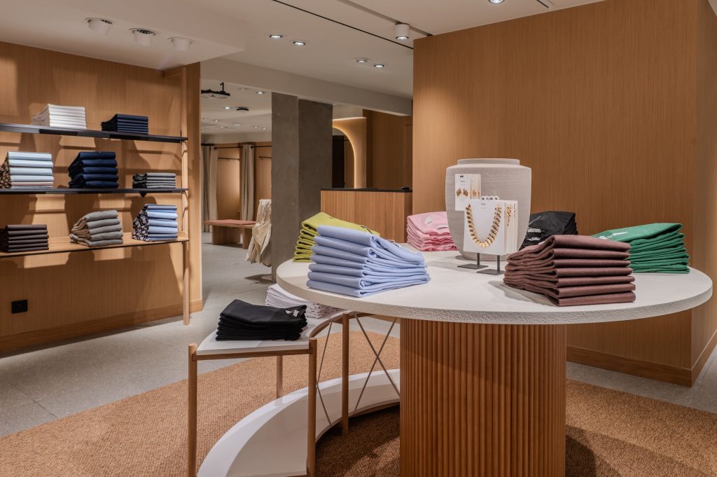Mobilier central rond dans la boutique MANGO Lyon avec vêtements pliés, accessoires et habillage bois