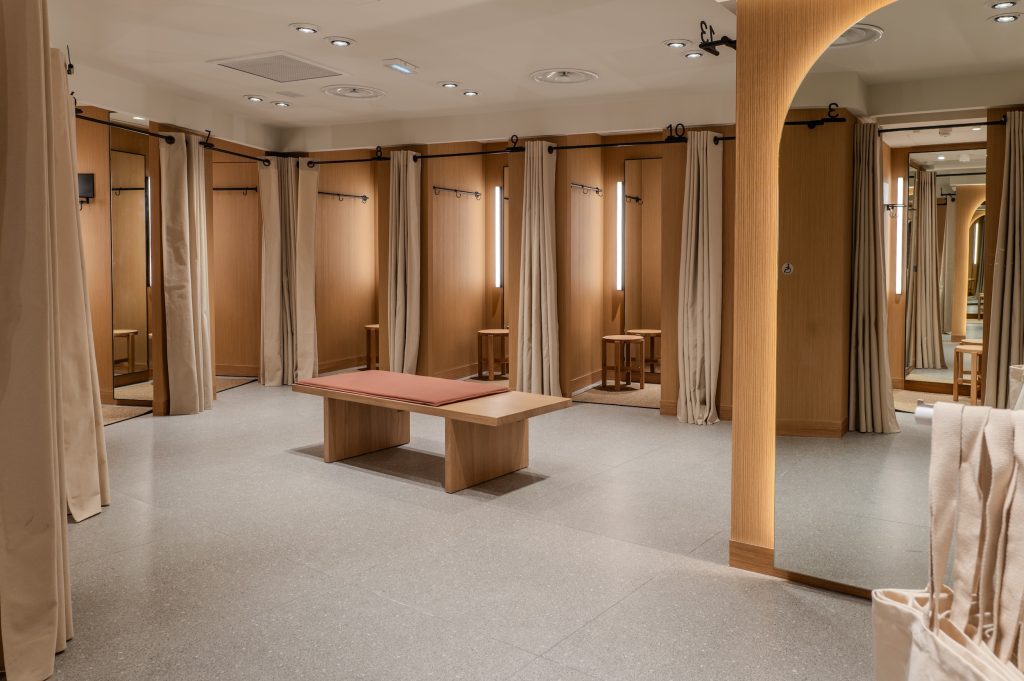 Cabines d’essayage de la boutique MANGO Lyon avec rideaux, miroirs, banquette centrale et habillage bois