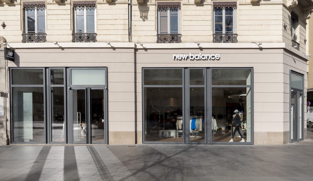 Mobilier central de présentation dans la boutique New Balance Lyon avec sneakers, textile et mannequin