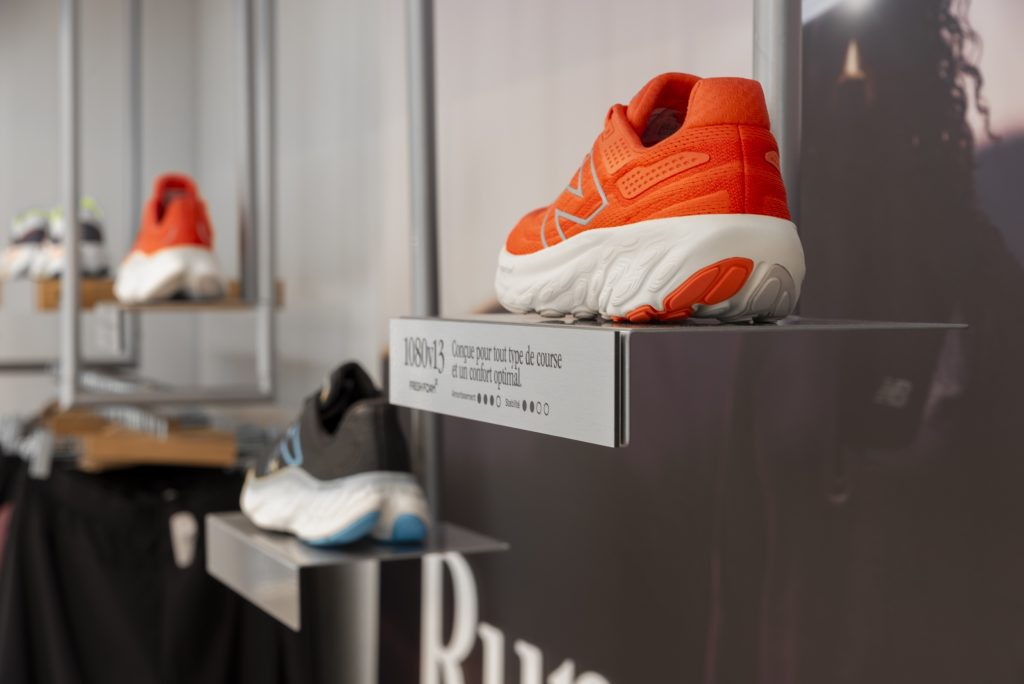 Sneakers New Balance présentées sur support mural dans la boutique Lyon avec signalétique running