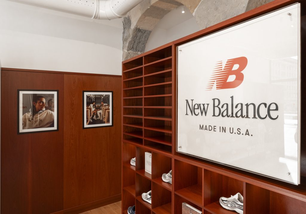 Signalétique New Balance Made in USA dans la boutique Lyon avec mobilier bois et arches en pierre