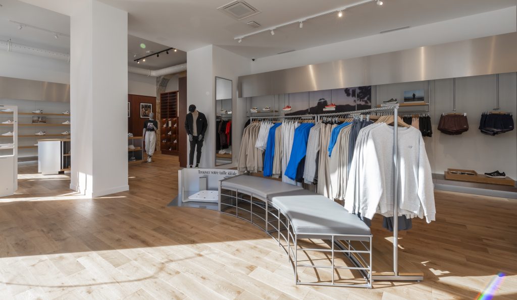 Espace textile New Balance Lyon avec portants vêtements, mannequin et mobilier retail