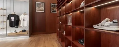 Intérieur de la boutique New Balance Lyon avec mobilier bois, linéaires sneakers et espace textile