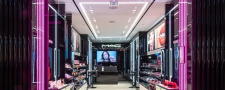 Intérieur de la boutique MAC Lyon Part-Dieu avec mobilier noir, éclairage scénographique et linéaires maquillage