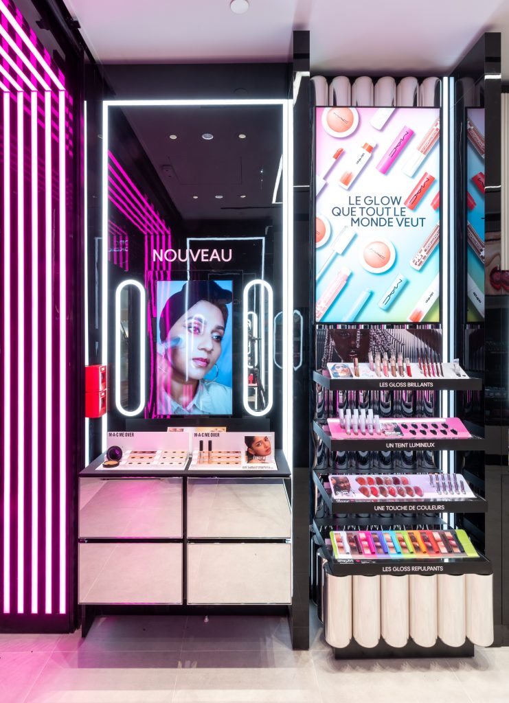 Produits maquillage MAC présentés dans la boutique Lyon Part-Dieu avec écrans, linéaires noirs et éclairage rose