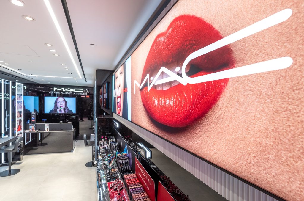 Grand visuel MAC Cosmetics avec logo lumineux et linéaires maquillage dans la boutique Lyon Part-Dieu