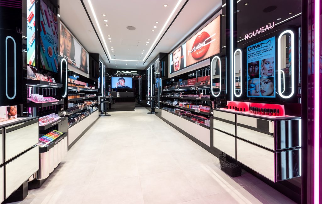 Linéaires de maquillage MAC dans la boutique Lyon Part-Dieu avec mobilier noir, miroirs lumineux et écrans digitaux