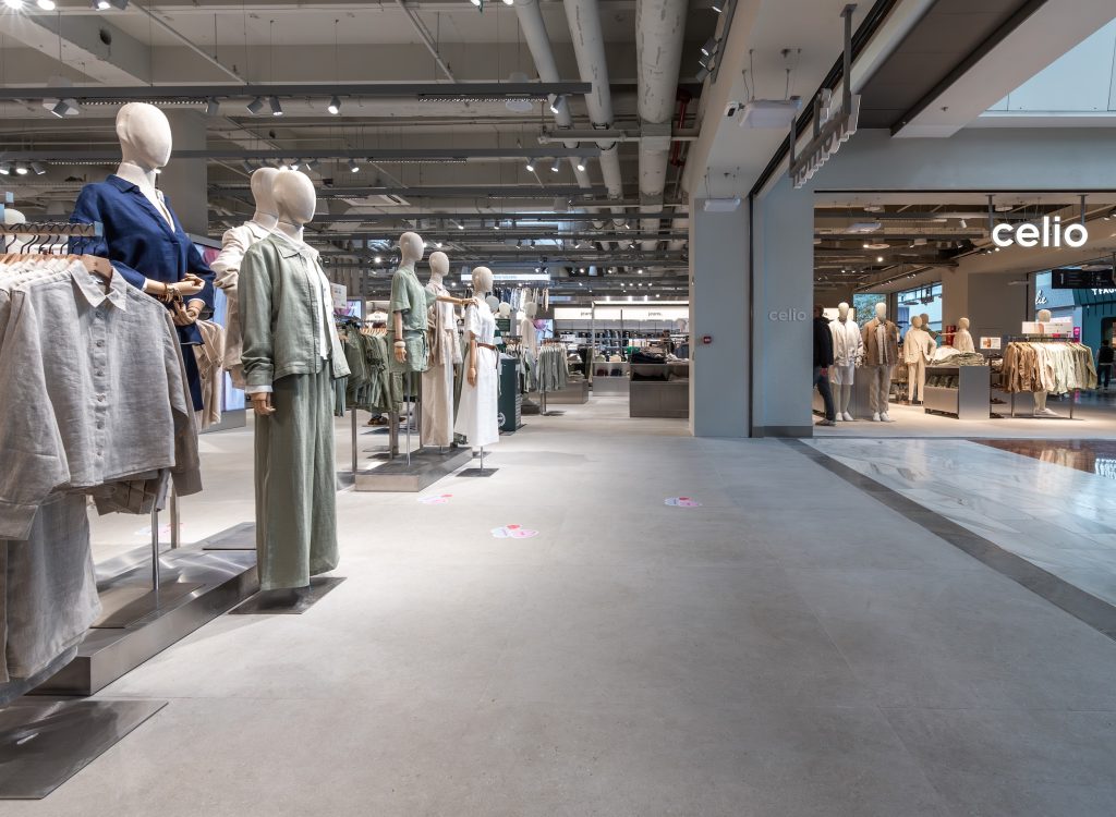 Rayons vêtements dans la boutique Célio Westfield Vélizy avec portants, tables de présentation et mobilier retail