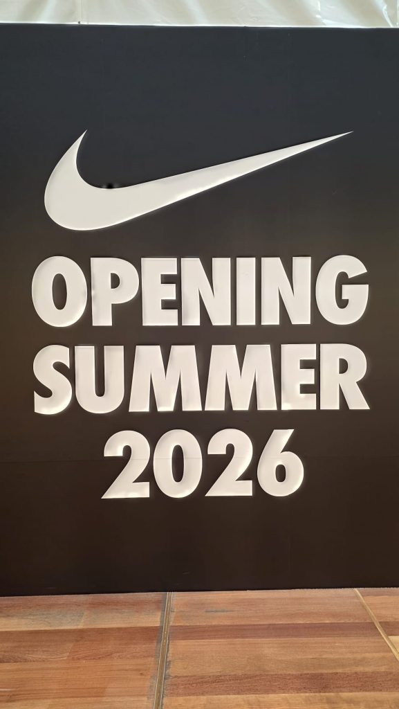 Panneau du logo nike accompagné du texte "opening summer 2026".