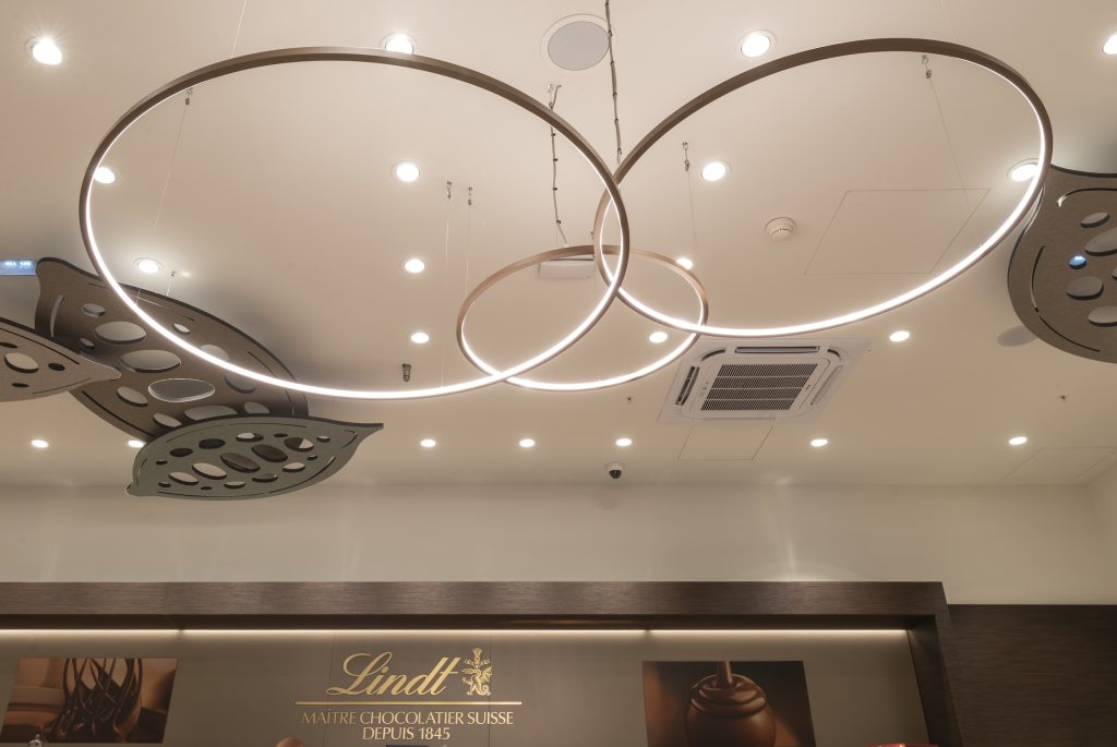 Luminaires circulaires et plafond décoratif dans la boutique Lindt rénovée à Nailloux