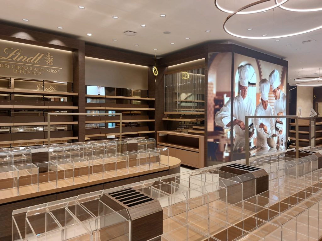 Agencement intérieur de la boutique Lindt Nailloux avec vitrines, mobilier chocolat et mur visuel