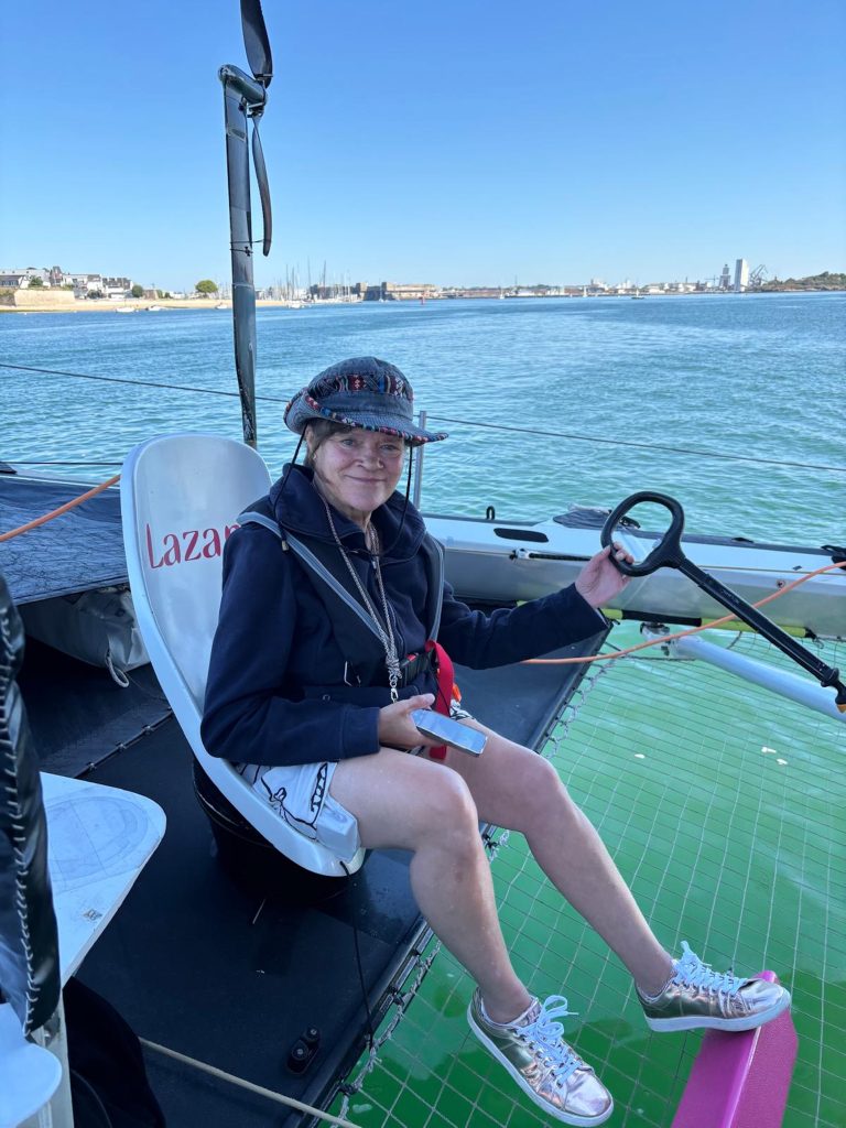Participante installée à la barre du trimaran Lazare lors d’une journée partenaires à Locmiquélic