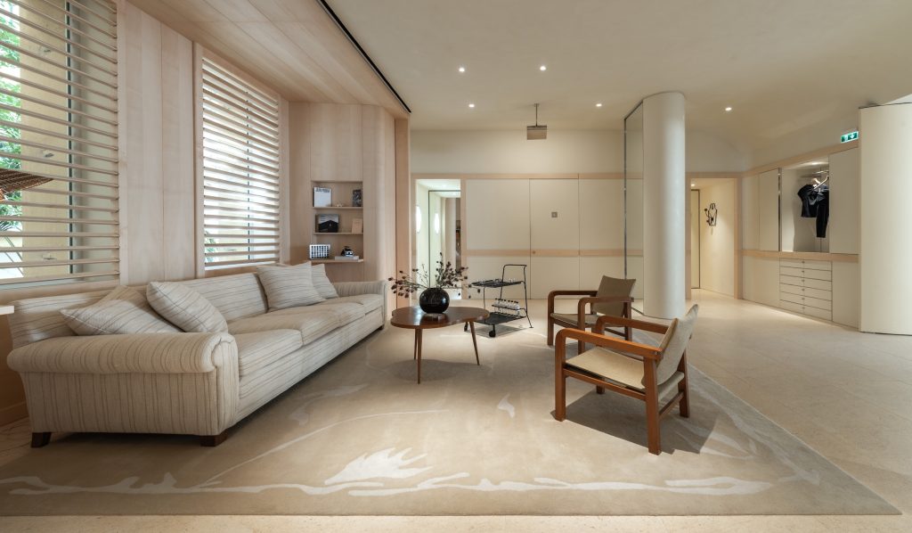 Espace lounge de la boutique Frame Cannes avec canapé, fauteuils, stores bois et mobilier intégré
