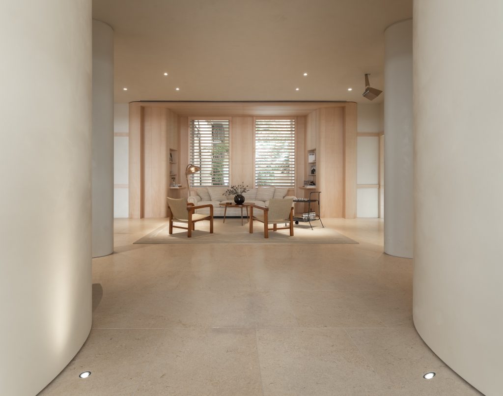 Espace salon de la boutique Frame Cannes avec canapé, fauteuils, bois clair et cloisons arrondies
