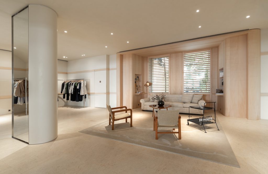 Espace salon Frame Cannes avec canapé, fauteuils, portants vêtements et finitions bois clair