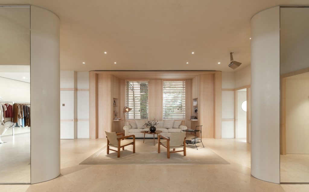 Vue frontale de l’espace salon Frame Cannes avec canapé, fauteuils, colonnes courbes et éclairage intégré