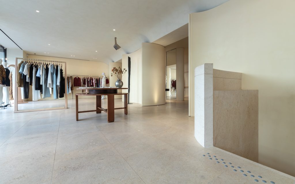Escalier en pierre et espace de vente de la boutique Frame Cannes avec table centrale et portants vêtements