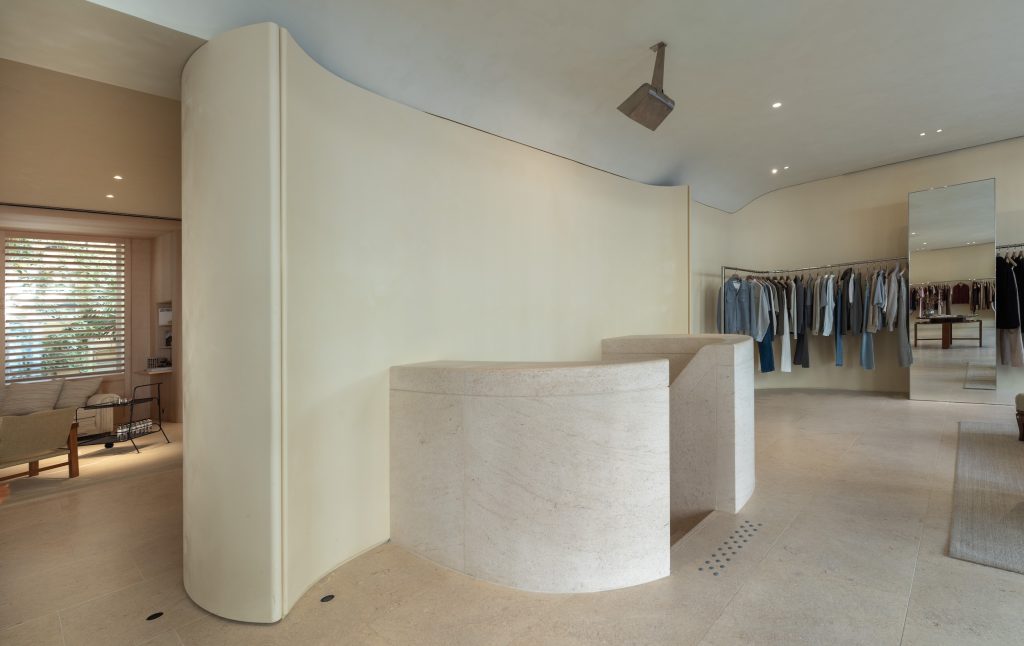 Cloisons courbes, escalier en pierre et portants vêtements dans la boutique Frame Cannes